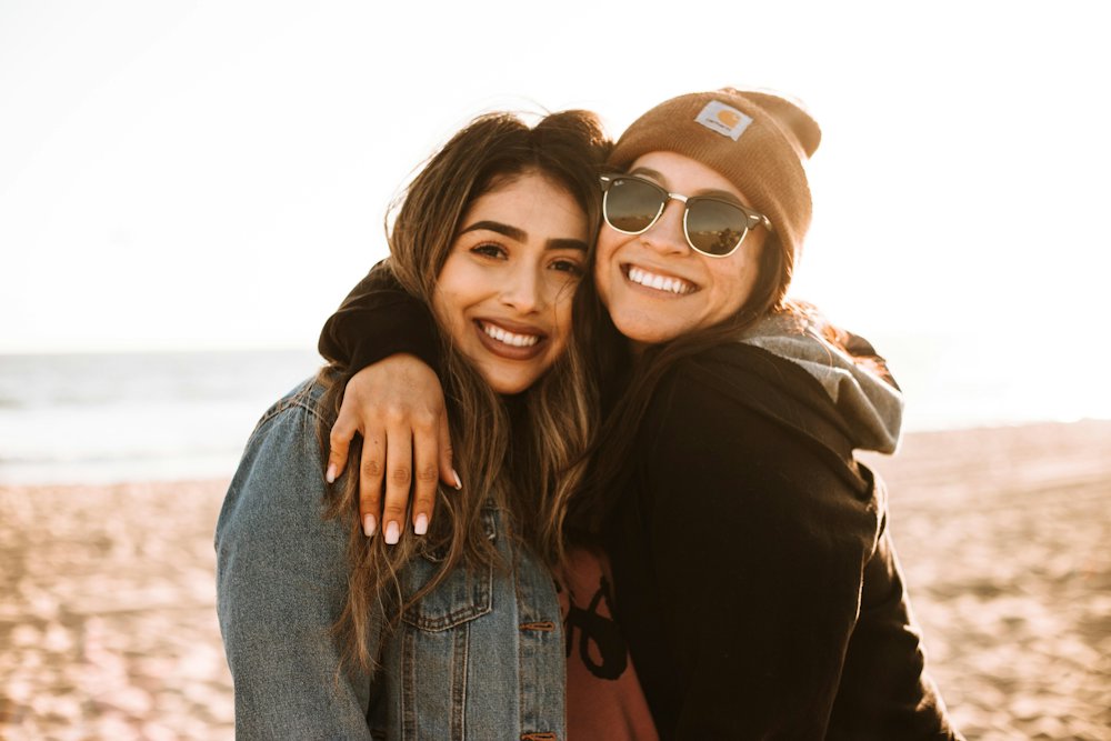 Two women hugging and smiling by the sea